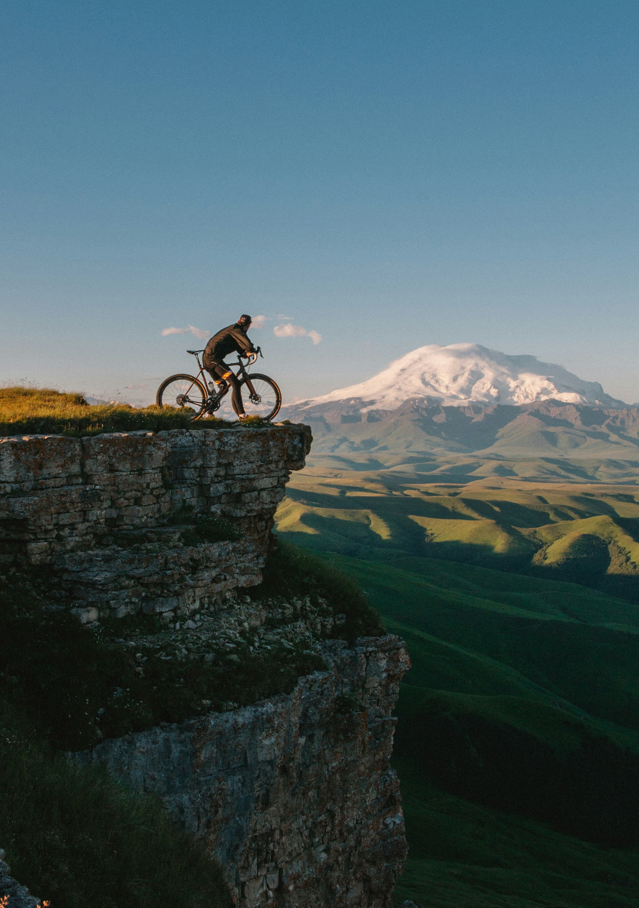 Cyclists riding a coastal road with sea views and a lighthouse on the horizon — one of seven scenic cycling routes in Europe featured in this guide.